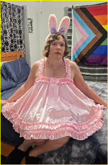 Sissy Kim sitting on the bed wearing bunny ears and his hopelessly feminine pink nightie